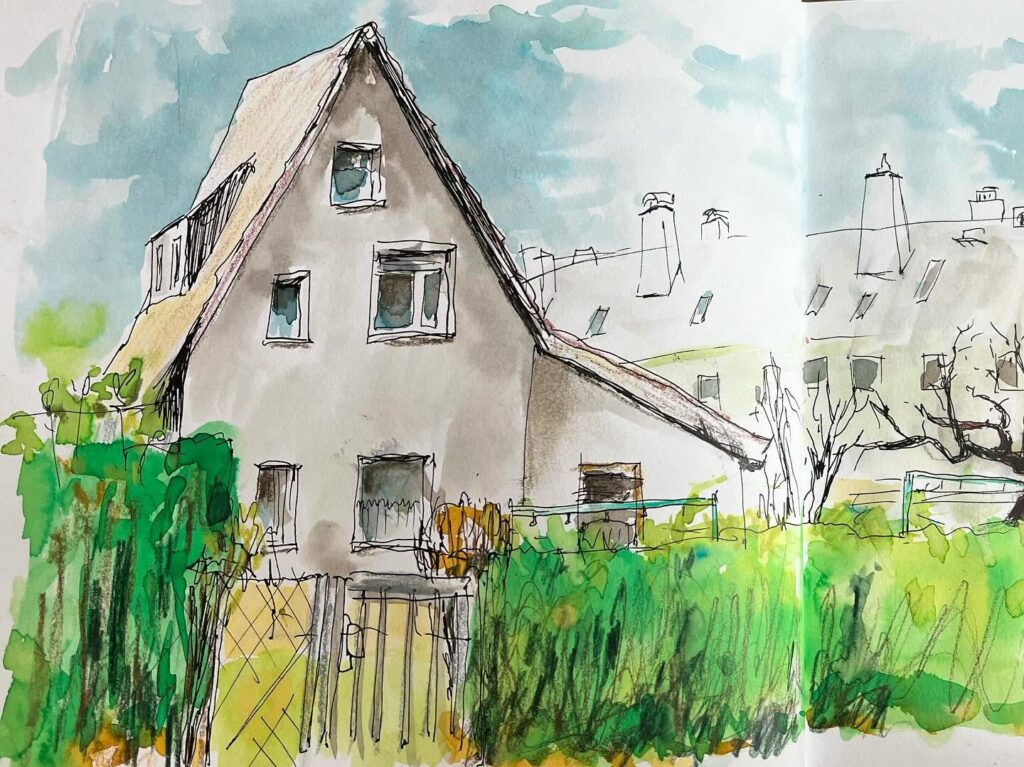 Aufgeschlagenes Skizzenbuch mit einer Garten- und Häuseransicht in Grün und hellem Blau.